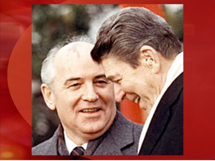 Two men smiling and conversing together outdoors.