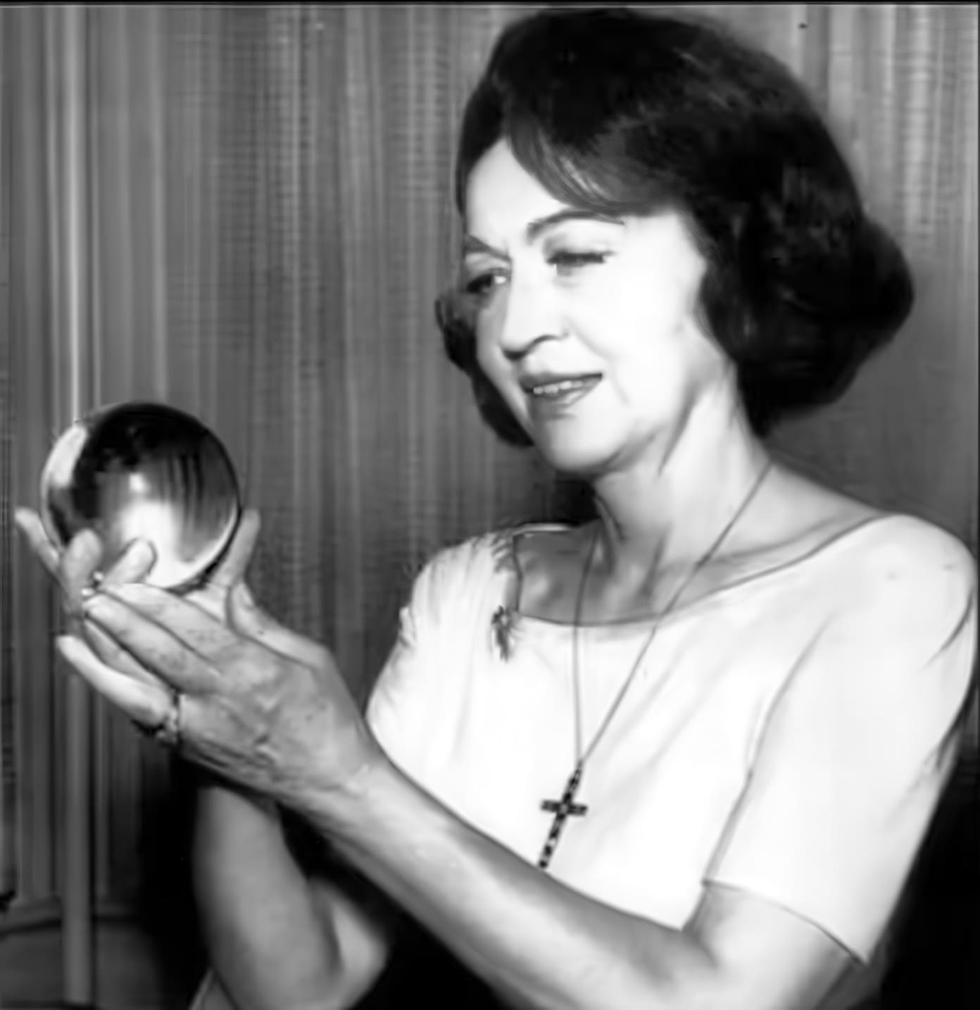 Woman holding a crystal ball, looking contemplative.